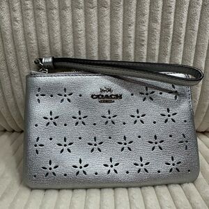 Coach Silver Wristlet Clutch w/ floral cutouts. New. Never used.blue interior.